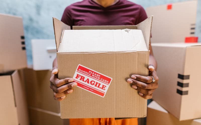 Packer holding a fragile-labelled moving box
