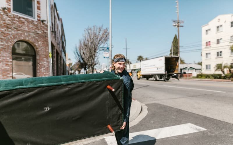 Mover carrying a sofa across the street for a single item move